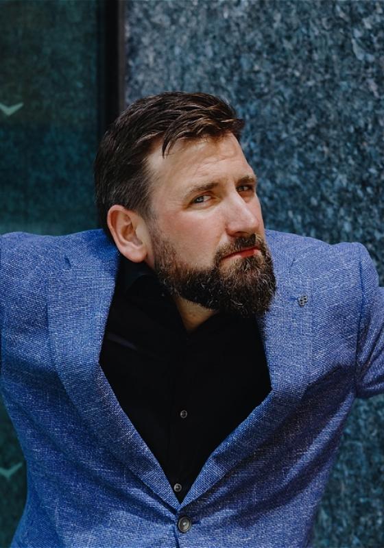 Garrett looking quizzically at the camera wearing a blue suit.