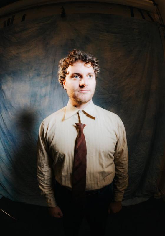 Photo of Jonathan in a brown shirt and tie.