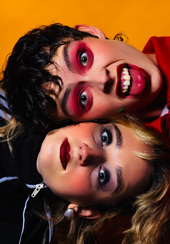 Close up photo of wo performers with their heads laid on top of one another.