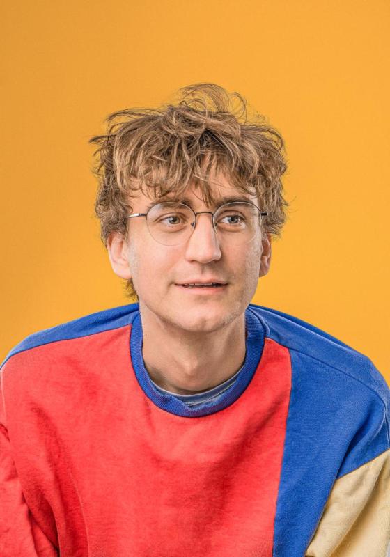 Headshot of Sam wearing a bright colourful jumper.