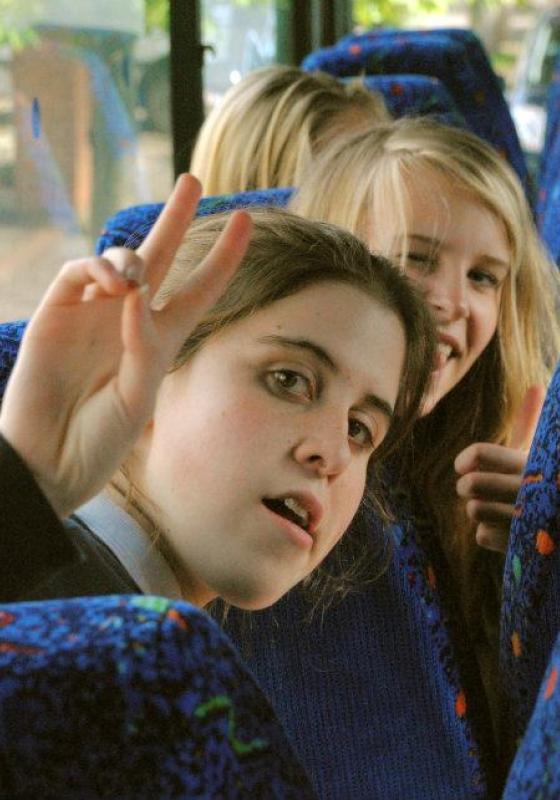 Photo of Ele as a school child on the bus giving the peace sign.