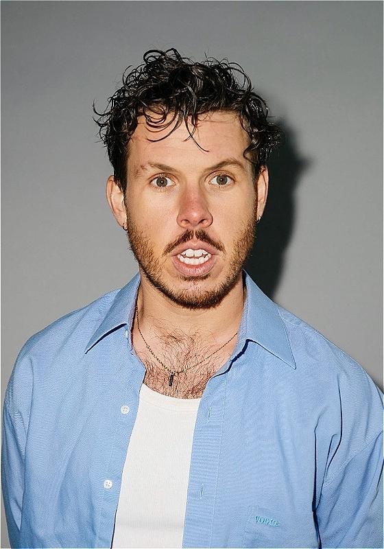 Photo of performer wearing a white t shirt and blue shirt.