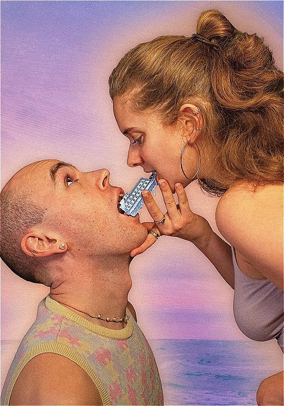 A man and a woman hold a single toy cruise ship between both of their mouths before a pastel purple sea background