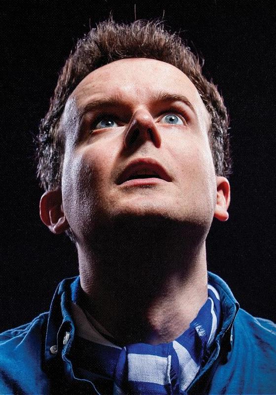 Close up of Andrew's face against a pitch black background. He is fearfully looking up. 