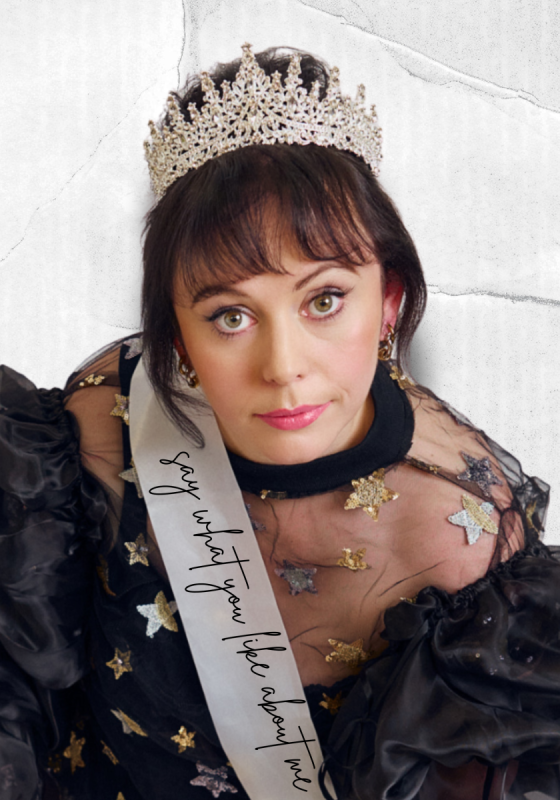 Amy looking up at the camera, wearing a tiara and a sash saying 'say what you like about me'. 