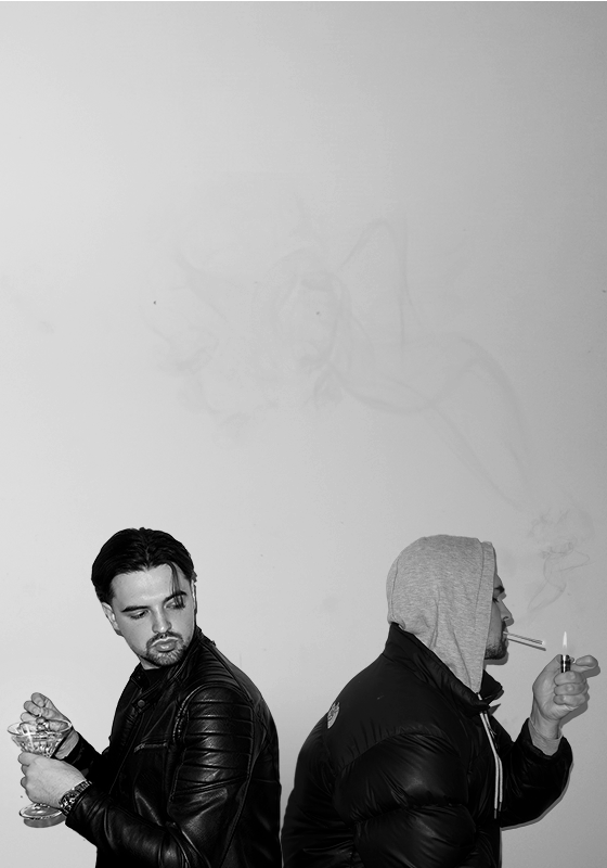 Black and white image of two versions of the same man sitting back to back. One wears a leather jacket and holds a martini glass. The other wears a grey hoodie and puffer jacket with the hood up and is smoking.