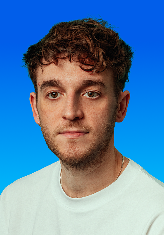 Dave staring ahead wearing a white t-shirt against a blue background.