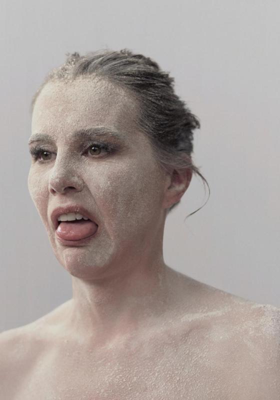 Kirsty has her hair pulled back and has white paint all over her face and bare shoulders, looking disgusted. 