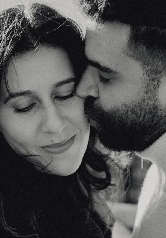 A black and white close-up image of the performers. One is being kissed on the cheek.