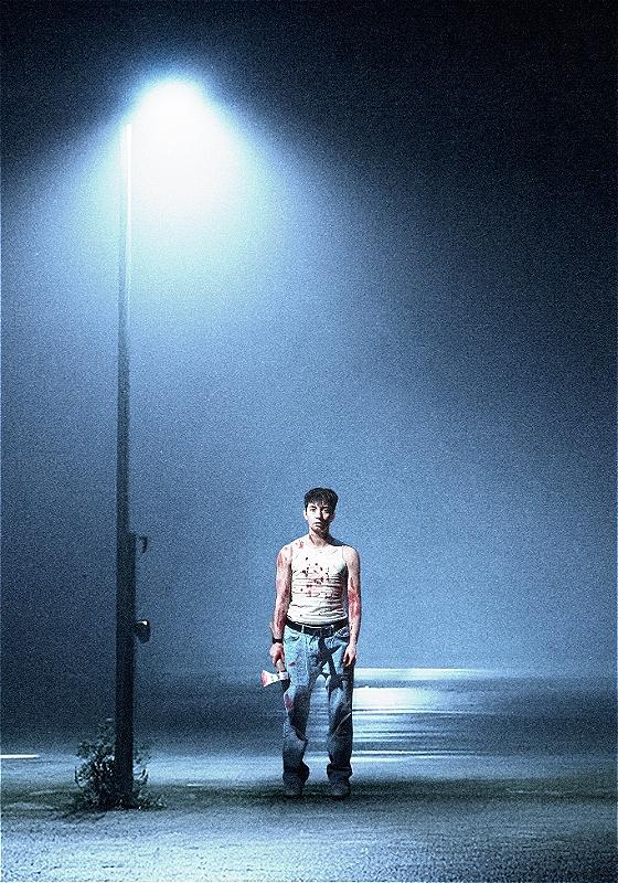 A person wearing a bloodstained vest and jeans stands in a dramatic blue lit scene. The path he stands on is visibly wet, and he is holding what appears to be an equally bloodstained axe.