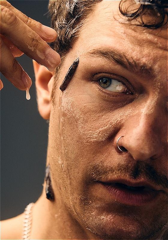 A closeup of an individual with slugs crawling across their face. Their face and hands are dripping with the left over mucus. 