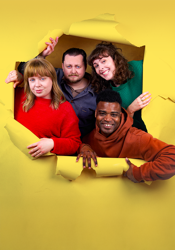 Four people peer through a yellow paper with torn edges.
