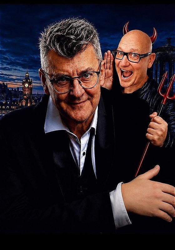 A person dressed in a suit smiles into the camera. Behind them as person dressed in devil horns and a mischievous expression looks as if they are mouthing something. London can be seen in the background. 