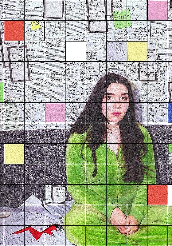 Performer in a green velour tracksuit sitting on the floor. Writing covers the walls behind her and a grid effect is over the camera. 