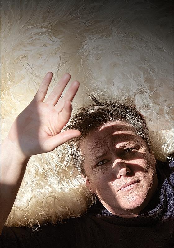 Hannah lying on a white rug, shielding their face from the sun.