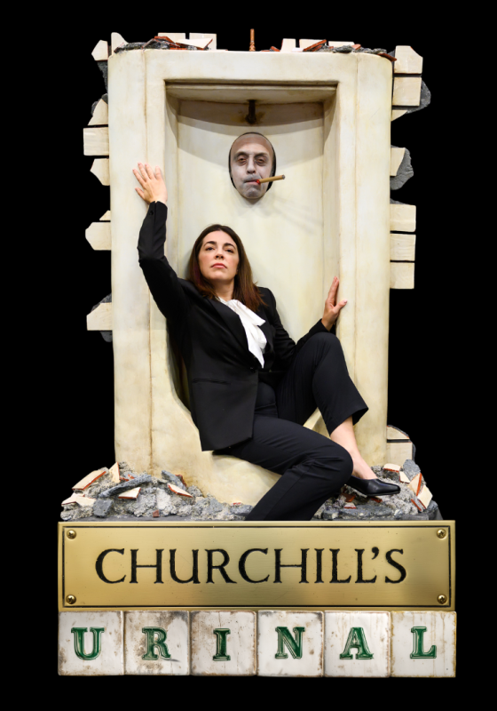 Woman wearing a suit crouch in a urinal with a man's face poking through the hole. The title of the show at the bottom.