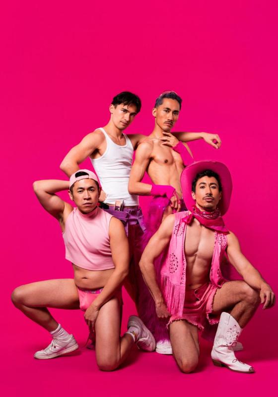The performers pose in front of a pink background