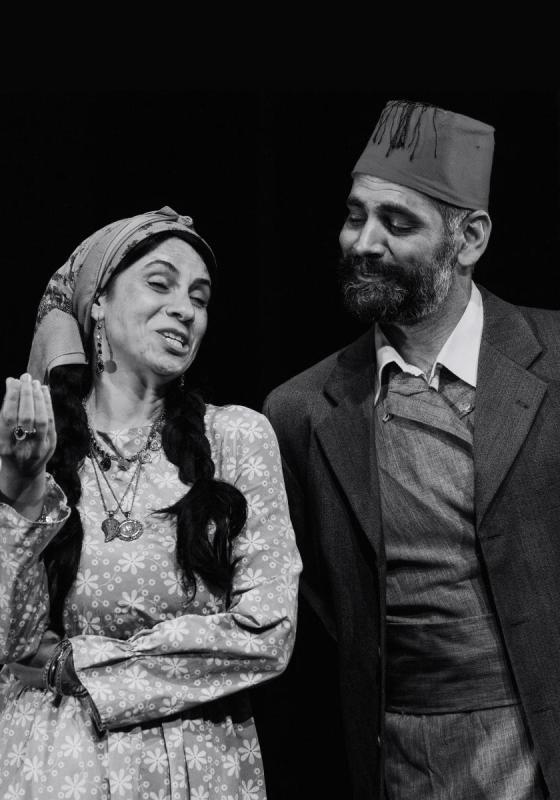 A man and a woman look engaged in happy conversation, against a black background.
