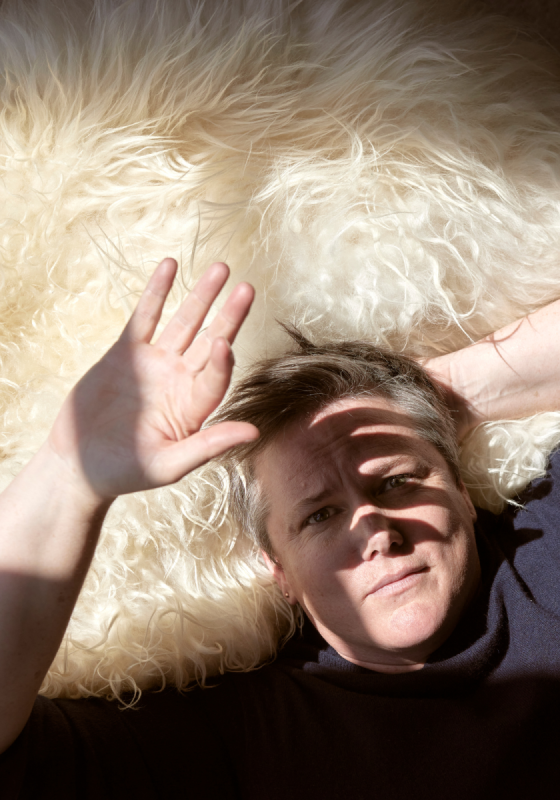 Hannah lying on a white rug, shielding their face from the sun.