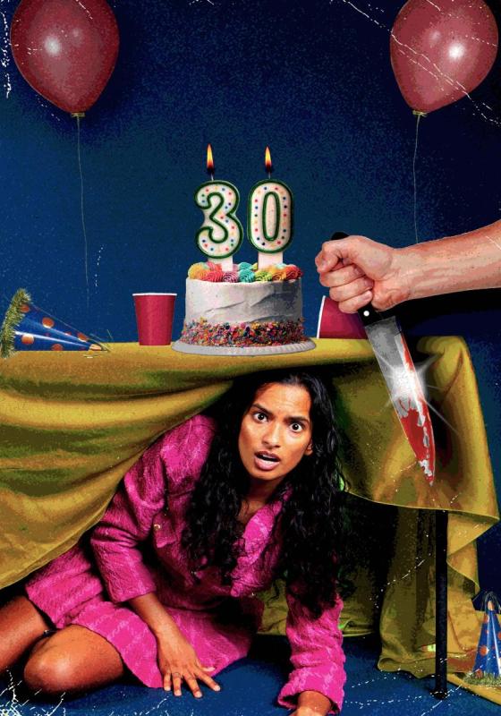 Abby hides under a table at a party. On the table there is a cake with '30' candles, and party cups and hats. In the foreground a hand reaches in from off-frame, holding a knife 