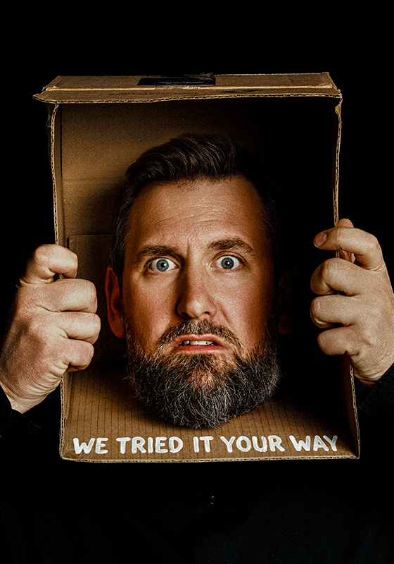Garrett Millerick's head is stuck in a cardboard box. The words 'we tried it your way' are written across the box in white paint.