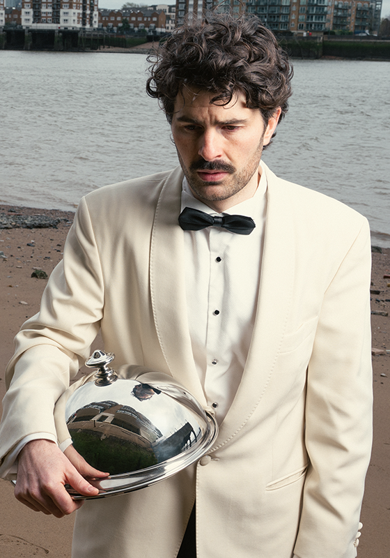 Paddy holding a cloche looking distraught on a bleak beach