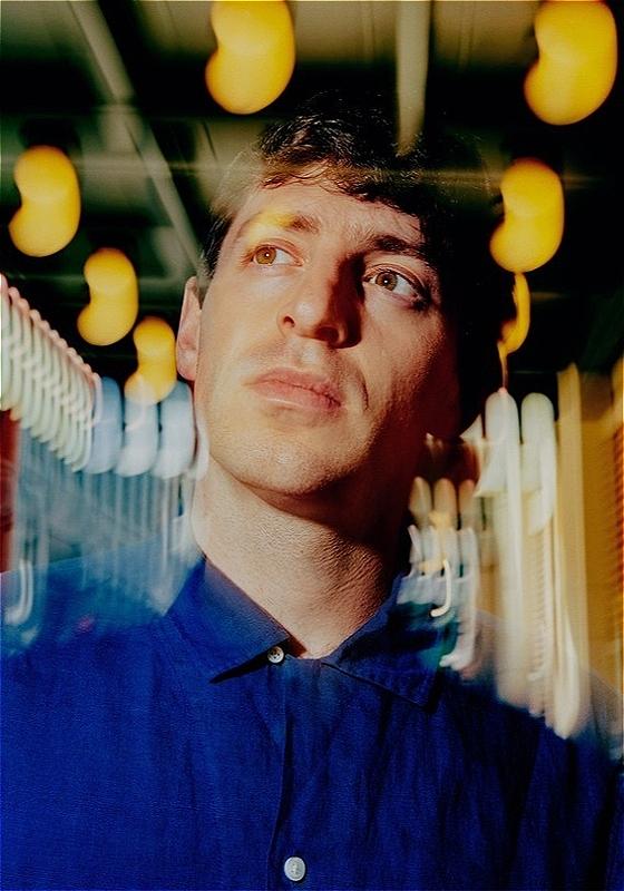 Blurry photo of Alex Edelman gazing off camera