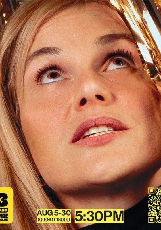 Davina, a white woman with blonde hair, looks up through gold ribbon curtains.