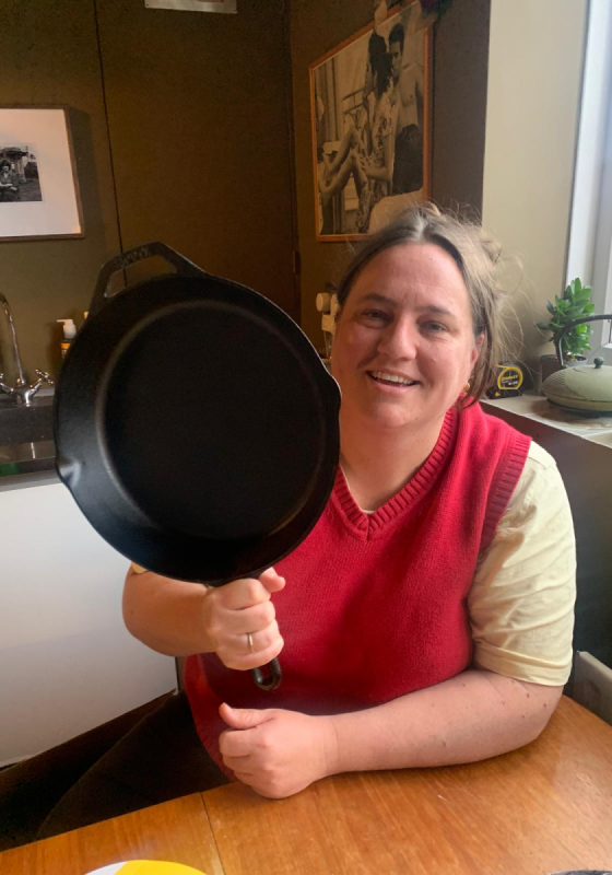 Alice Sneddon holding up a frying pan in a kitchen.