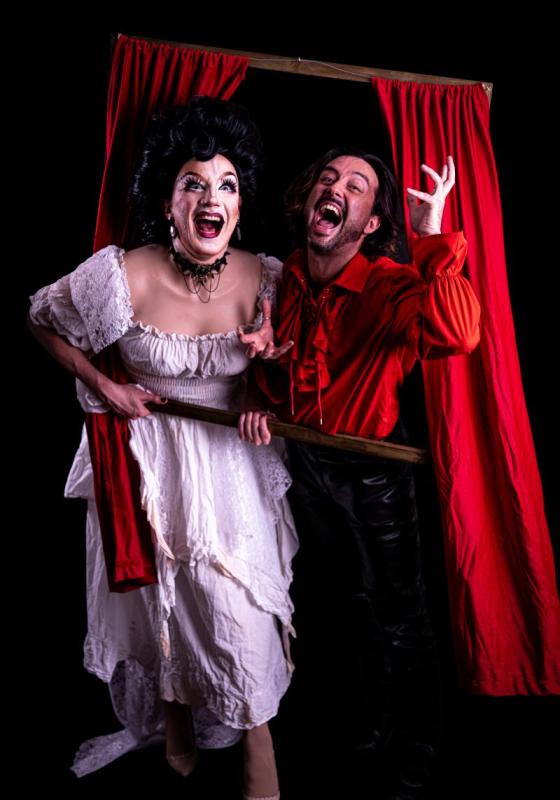 The performers huddle together around a window frame prop in front of a black background