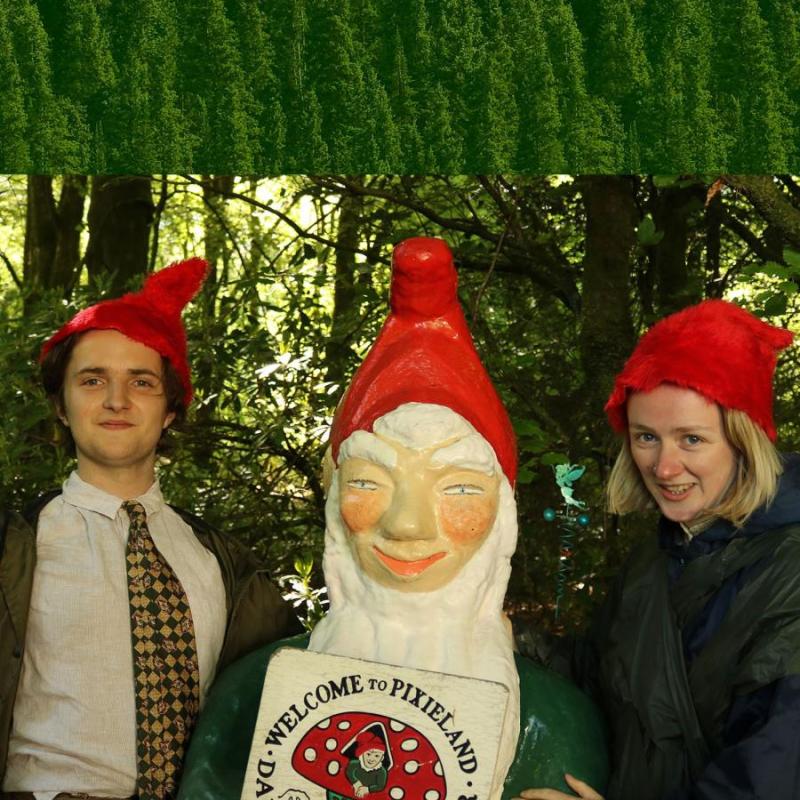 Ada and Bron stand either side of a large garden gnome wearing matching hats