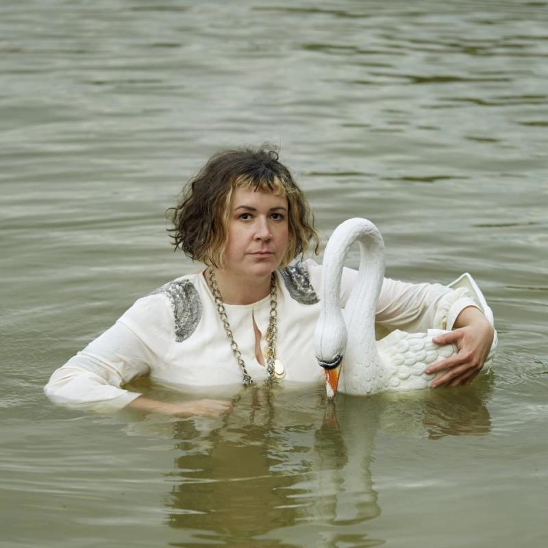 Amy stands in chest high water holding an ornamental toy swan.