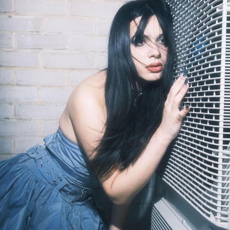 Enxi in blue dress against a white wall
