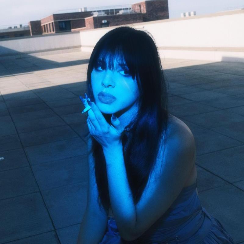Enxi in blue light, holding a cigarette