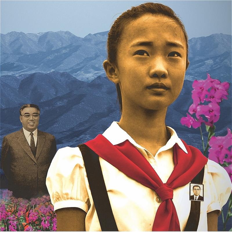 A close-up of a young girl amidst flowers and the mountains. A man stands in the background wearing a suit.