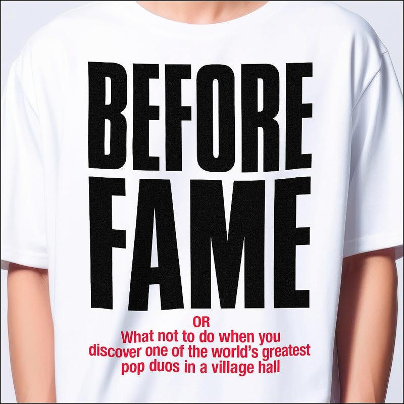 A person wearing a white t-shirt with black text that reads "BEFORE FAME" in large letters and below in smaller red text "OR What not to do when you discover one of the world's greatest pop duos in a village hall".