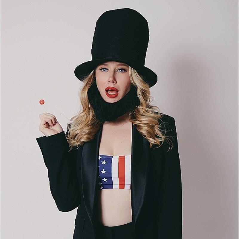 Woman in business attire and hat channelling Abraham Lincoln holding a red lollipop