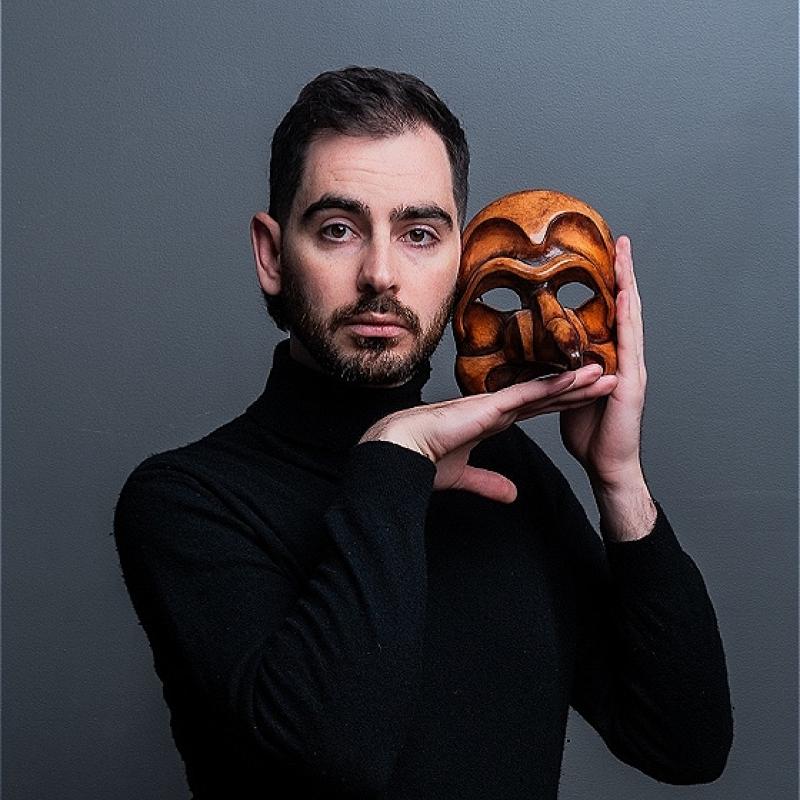 A man holding a wooden mask in front of his face, showcasing traditional artistry and cultural significance.