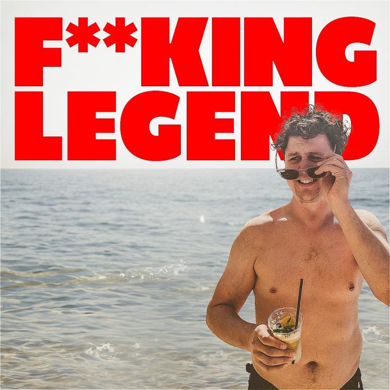 A man standing at the beach holding a drink and laughing while on the phone, with bold red text saying "F***ING LEGEND" across the top.