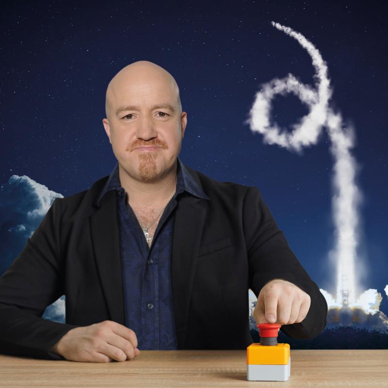 Andy holds his finger next to the big red button with smoke from a rocket appearing behind.