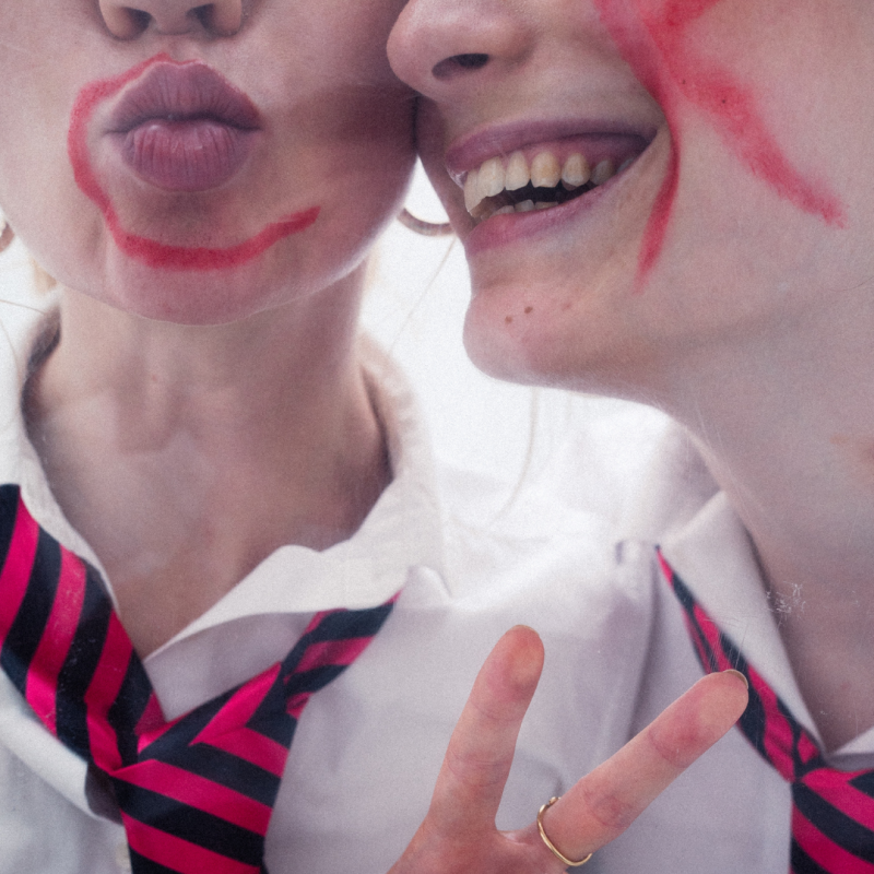 A closeup of two young girl's faces in school uniform. One has a C on their face and the other has a K in red pen.