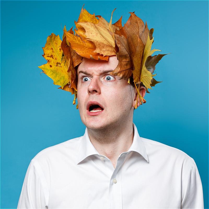 An anguished looking Andrew Doherty wears a laurel wreath made of leaves on their head, staring out at the viewer.
