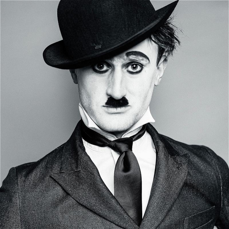 A black and white close up photograph of a performer dressed and styled as Charlie Chaplin.