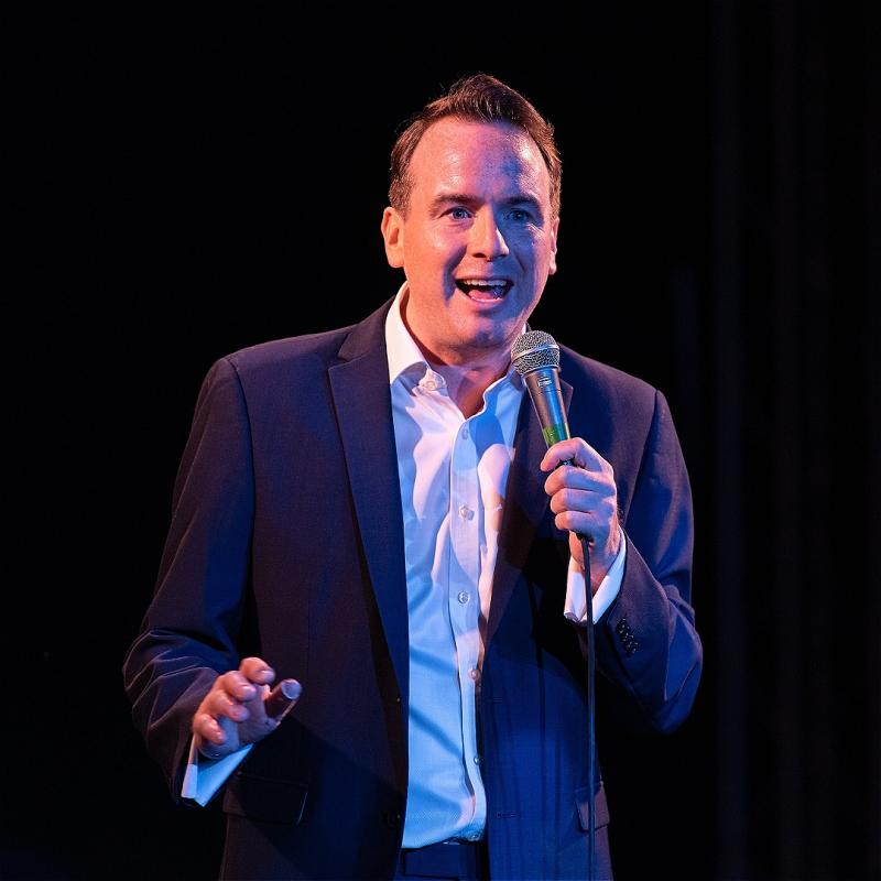 Photo of Matt Forde on stage holding a microphone.