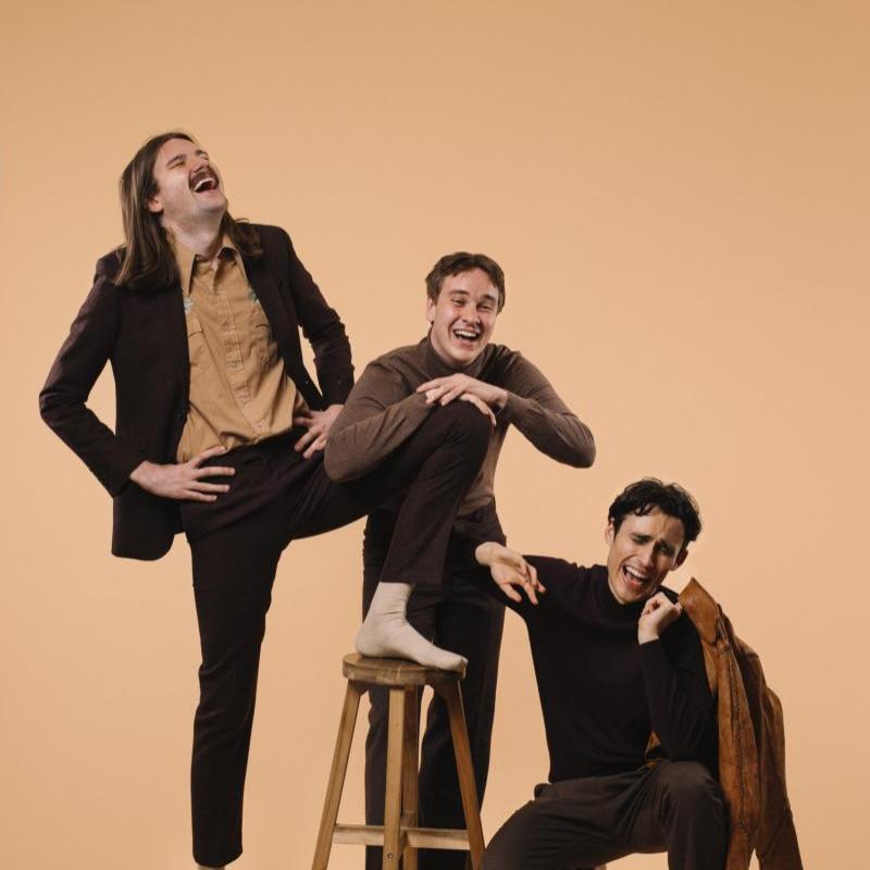 The cast of crybabies laughing intensely wearing brown and earth tones