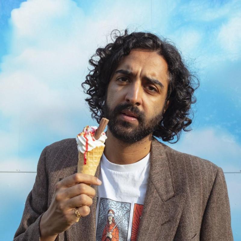 Rajiv looking pensive holding a ice cream cone against a bright blue sky