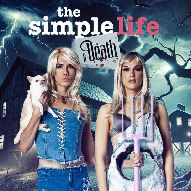 Performers stand in front of a haunted castle one with one holding a dog and the other with a pitchfork.