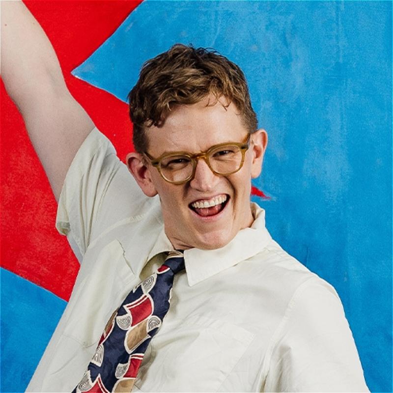 Chris with a cheesy grin on his face wearing a white short-sleeved shirt and tie.