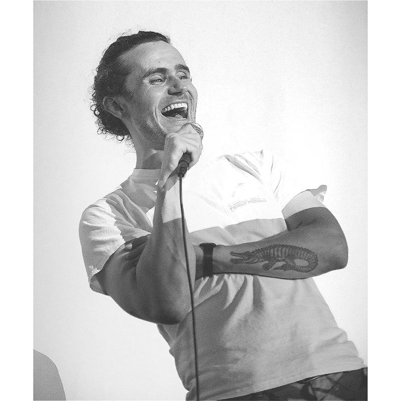 Black and white image of the comedian on stage mid laugh
