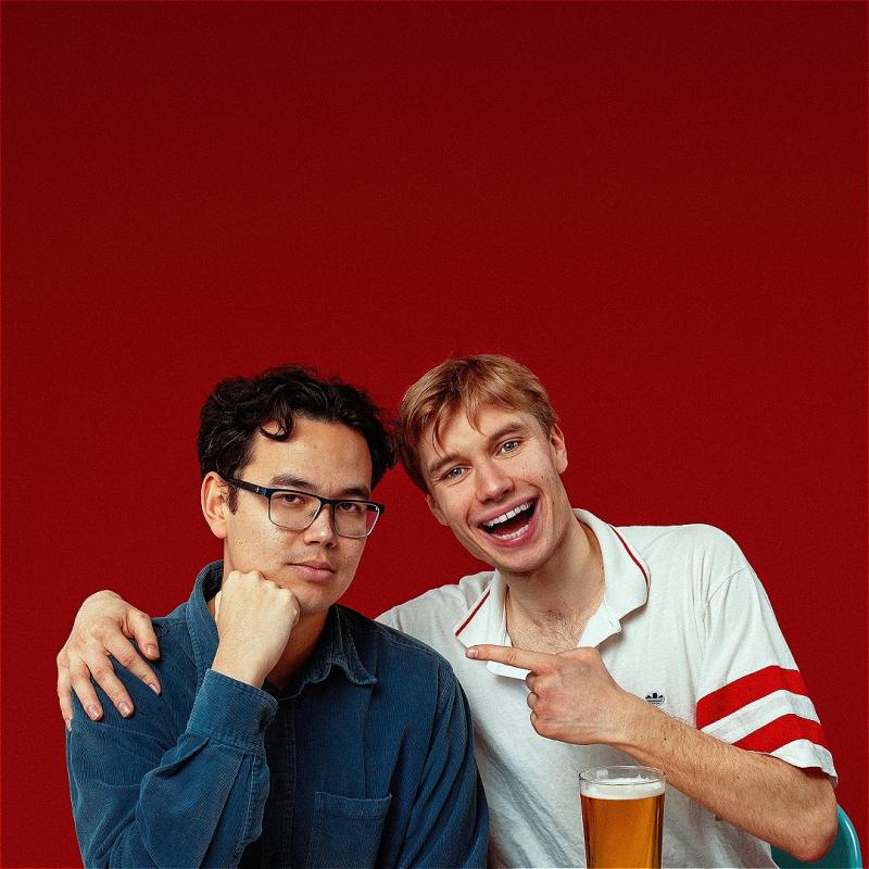 Two performers laughing and smiling, one holding a pint, the other a burger.